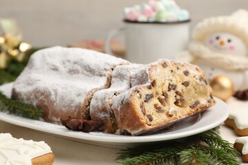Cut traditional Stollen cake, cookies, drink and Christmas decor on white table, closeup
