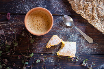 Top-view cozy winter scene: homemade cookie dusted with powdered sugar, hot coffee in a cup, and a tea spoon on a rustic wooden table. Warm inviting atmosphere, soft natural lighting. Perfect for food