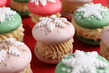 Festively decorated macarons on red background, closeup. Christmas treat