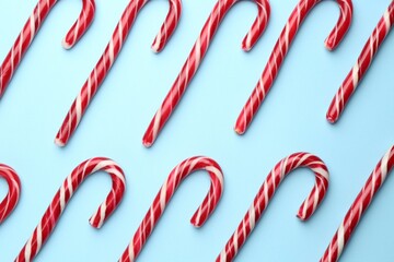 Tasty candy canes on light blue background, flat lay. Merry Christmas and Happy New Year