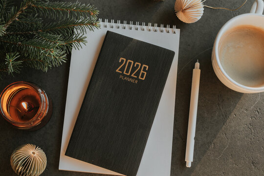 Stylish Desk Setup With 2026 Planner, Notebook, Pencil, Glasses, Fir tree Branch and Coffee on Wooden Surface - Powered by Adobe
