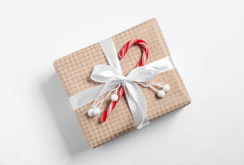 Decorated Christmas gift with candy cane on white background, top view