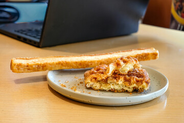A croffle with cinnamon sugar topping and a slice of garlic bread served on a gray ceramic plate over a wooden table in natural light. Perfect for bakery advertising, cafe menu