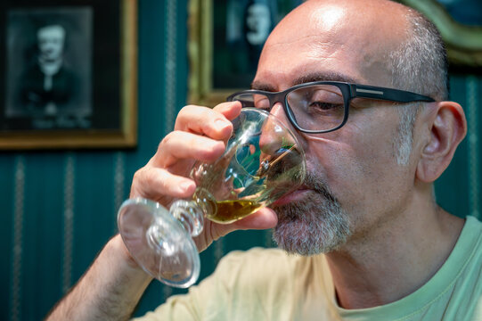 Prague, Czech Republic, August 8, 2023. Portrait of a middle-aged man drinking absinthe. Relaxation and meditation in a bohemian setting. Artistic lifestyle.