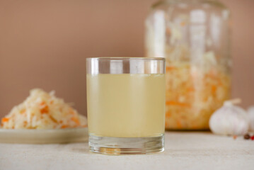 Homemade sauerkraut juice or brine with sauerkraut salad in a plate and jar on a table.