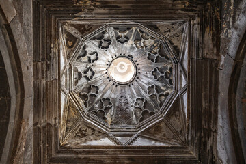A ceiling of An Armenian Saghmosavanq monastery church with a large round light in the middle