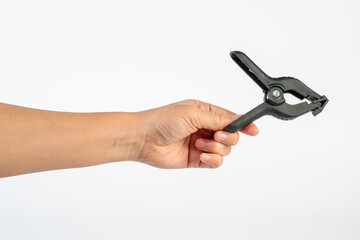 A studio shot of a black plastic spring clamp in hand isolated on a white background