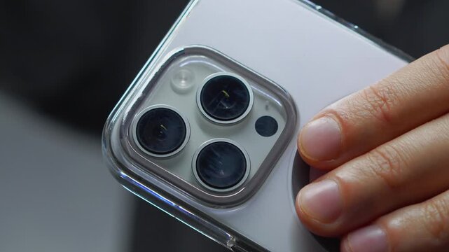 A person holding a white mobile phone with a camera.
Lens on the back of the smartphone.
Photo taken with a phone and a modern camera with zoom on the phone.
Lens, smartphone, phone, mobile