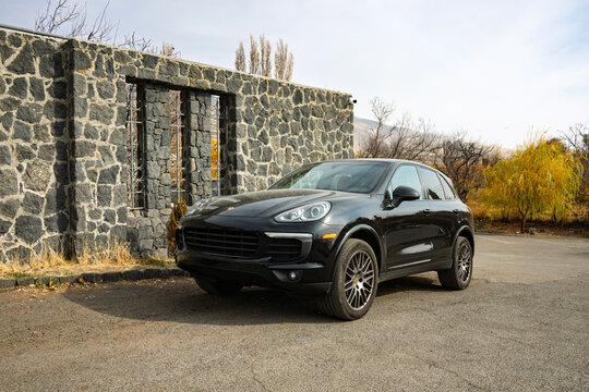 A black car is parked in front of a stone wall