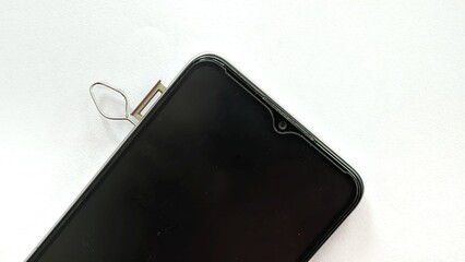 Close-up view of a smartphone's dual SIM card tray and MicroSD slot being removed with an ejector pin.