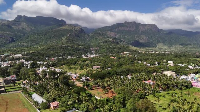 Majestic aerial panorama of the Western Ghats Courtallam, showcasing a forested valley town, flowing waterfalls, and monsoon clouds embracing the mountains.