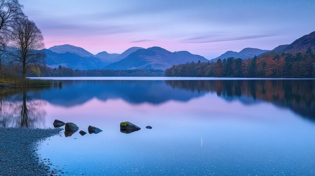 Serene lake view with mountains at twilight, calm waters reflecting the colorful sky, a perfect nature scene for relaxation.