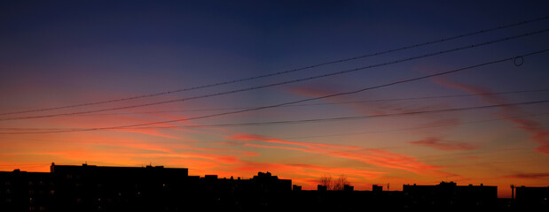 Picturesque sunset urban sky background with dark silhouettes of the houses at the distance, sunset sky in the city
