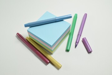 Blank colored notes and colored markers on a white background