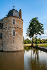 Château de Lavaux-Sainte-Anne with its stone towers reflected in the calm moat under a blue sky offers a peaceful and historic scene in the Belgian countryside surrounded by nature and architectural b