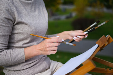 Close-up of artist hands holding painting brushes.