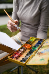 Close-up of artist mixing colors on watercolor palette.