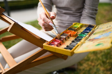 Close-up of artist mixing colors on watercolor palette.