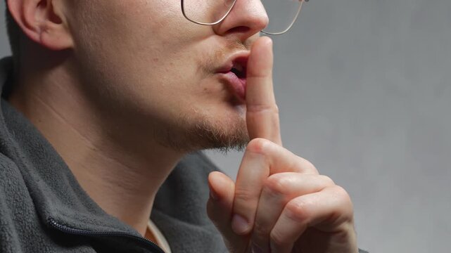 The finger gesture for silence.
A man signals that people should not speak loudly and should remain quiet.
The man touches his index finger to his lips.
Silence, shh, mouth, lips, index finger