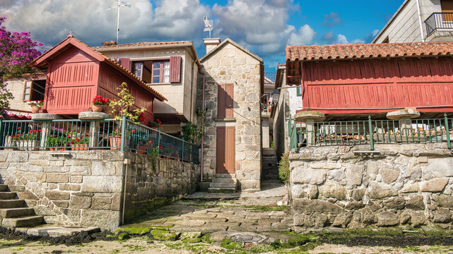 Casas de piedra y tradicionales h&oacute;rreos gallegos pintados de rojo en la villa de Combarro, Espa&ntilde;a. Con cielo editado