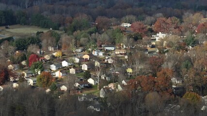 Sweeping aerial panorama of a peaceful American suburban landscape among rolling hills, rows of houses and vibrant autumn trees in midday light, evoking tranquil living and green connectivity. - Powered by Adobe