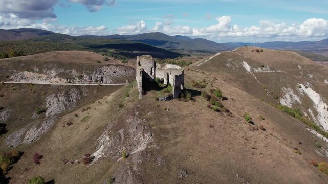 Aerial drone view of the medieval Bjelaj Fortress near Bosanski Petrovac, Bosnia and Herzegovina. The ancient ruins stand on a rocky hilltop surrounded by dramatic mountain scenery and open landscapes