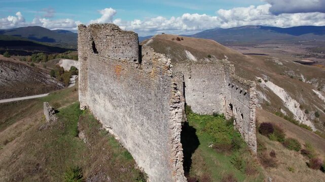 Aerial drone of Bjelaj Fortress near Bosanski Petrovac, Bosnia and Herzegovina. The medieval fortress walls rise above the rugged landscape, showing detailed stonework and panoramic mountain scenery