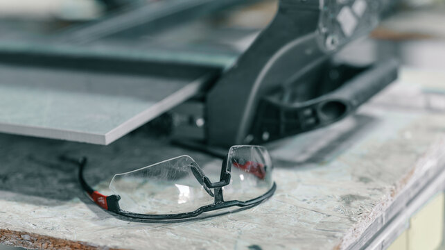 Safety glasses and tile cutter on a construction site, ready for work