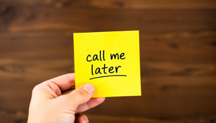 - Hand holding yellow sticky note with call me later on wood background