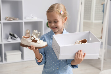 Little girl with pair of beautiful shoes in box at shop