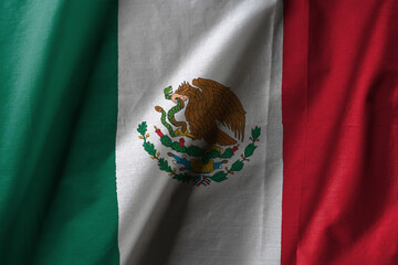 Mexican flag with vertical green, white, and red stripes, featuring the national coat of arms an eagle holding a serpent in its beak and talon, perched on a cactus in the center.