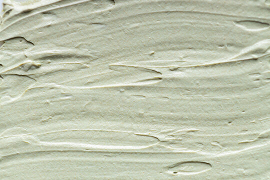Macro texture of soft green clay mask spread in smooth waves, creamy skincare product surface with natural matte finish ideal for beauty, spa, cosmetic and wellness concepts