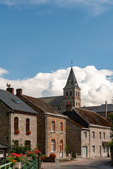 Traditional stone houses with flower boxes and a church tower in the historic village near Château de Spontin in Belgium showcasing authentic architecture and rural European charm under a vivid sky.
