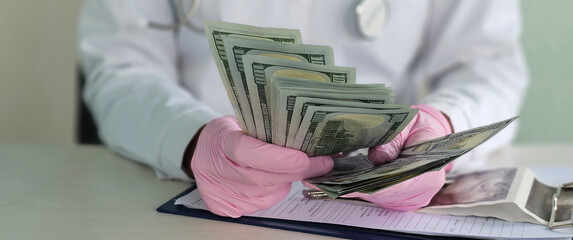 The doctor counts money at the table, closeup