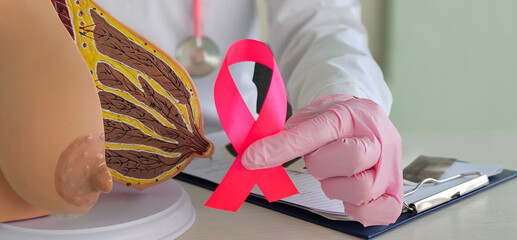Female gynecologist doctor holds pink ribbon as symbol of breast cancer awareness. Cancer research