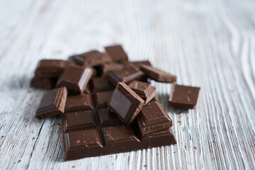 Pieces of chocolate on a wooden background. Selective focus.