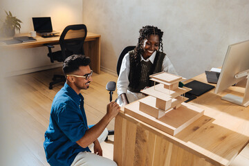 Two young architects discussing a building model in a modern office setting