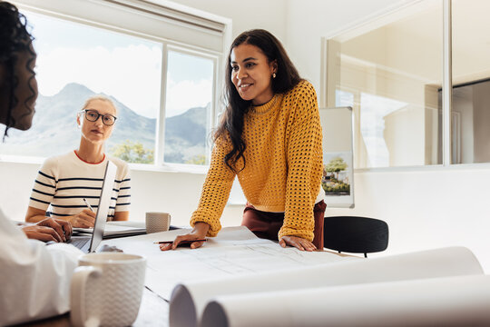 Team of female architects discussing design plans at a professional office workspace. - Powered by Adobe