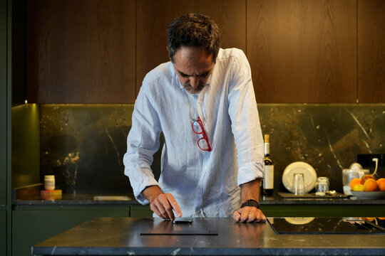 Adult man using smartphone in modern smart kitchen