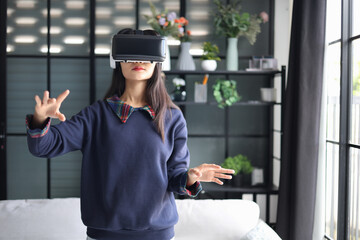 Young asian woman wearing virtual reality glasses, hand touching the air. VR headset. VR concept.