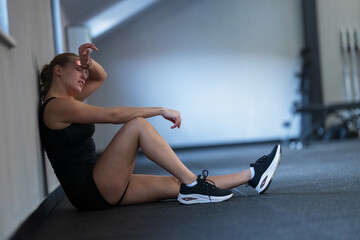 Fitness enthusiast taking a break after an intense workout session in a gym space during the...