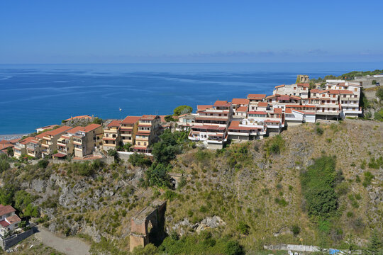 Scalea coastal town buildings overlooking Tyrrhenian sea. Scalea buildings on a rocky hillside facing clear blue sky and ocean.