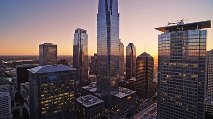 Dynamic sunset over modern city skyline with helicopter landing pad, perfect for business travel promos and urban development projects with a touch of sophistication and modern elegance