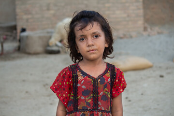 Rural village girl standing outdoors in traditional colorful dress, natural light portrait with calm and innocent expression