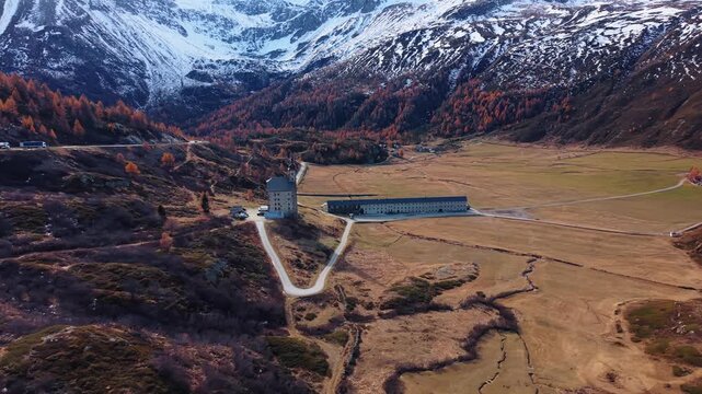 Aerial view of Simplon Hospice with its stoic architecture contrasting sharply with the rugged terrain, under the gaze of snow-capped mountains, Simplon Hospice, Wallis, Switzerland.