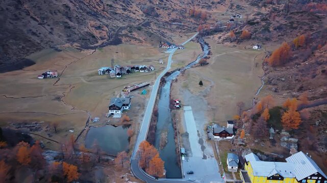 Aerial view of the village nestled in the valley, with a stream running alongside the main road, offering a tranquil scene, Formazza, Piedmont, Italy.