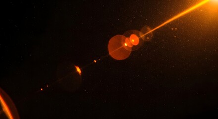 Abstract glowing orange lens flare effect with small particles and starlike dots on a dark background, representing light and energy in space