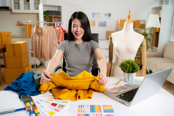 Female fashion designers design a product using a laptop computer with a digital tablet in a modern studio in the morning.
