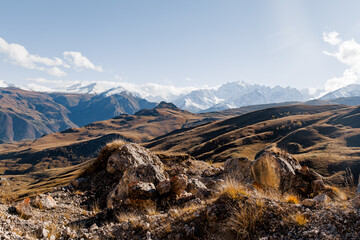 Snow-capped mountains in Kabardino-Balkaria under a cloudy sky. The landscape features rugged peaks and valleys, showcasing the natural beauty of the region.