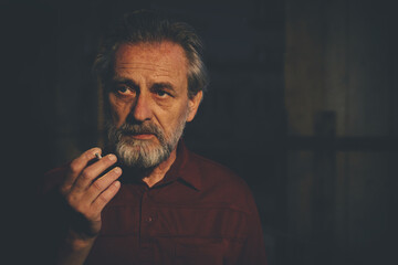 Older man in red shirt waiting for something and smoking on night city location